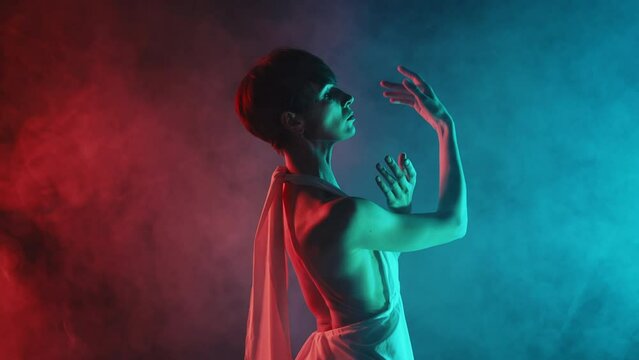 Gorgeous flexible woman with bare back performing amazing modern choreography - elegant contemporary style dance in dark studio. Freestyle hands movements 