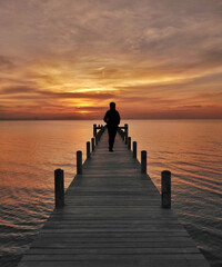 Silhouette of man on lake pier