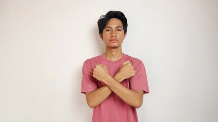 Young Asian man posing with crossed arms on an isolated white background. refusing, saying no, blocking gesture
