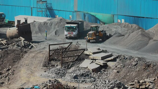 Dump Truck Unloads Crushed Stone For Construction Of New Road. Front Loader Pours Mountains Of Rubble. Preparing Road. Men At Work. Time Lapse, Timelapse, Time-lapse. Loading And Unloading Operations.