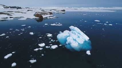 Aerial flight over Antarctic iceberg amid ocean. Winter seascape reflecting climate change. Drone...