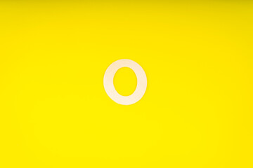 Letter O in wood on yellow background