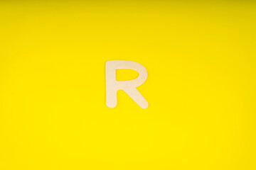 Letter R in wood on yellow background