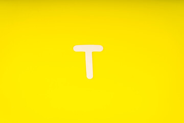 Letter T in wood on yellow background