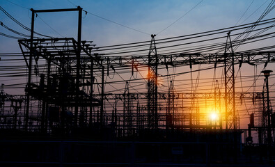 Silhouette of electricity transmission pylon at sunset sky. High voltage electric transmission tower.