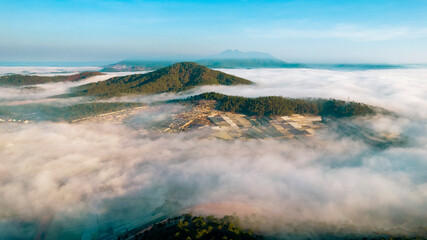 a breathtaking view of Dalat City enveloped in mist, with mountains, forests, and buildings peeking through the serene clouds under the soft morning light.
