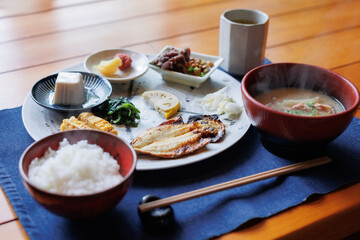 Japanese breakfast includes grilled fish, miso soup, tofu, rice, Japanese pickled vegetables, and Japanese green tea.