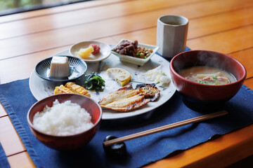 Japanese breakfast includes grilled fish, miso soup, tofu, rice, Japanese pickled vegetables, and Japanese green tea.