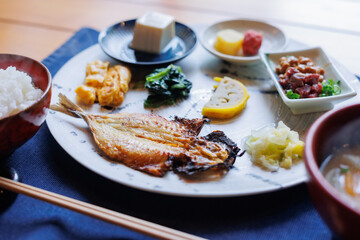 Japanese breakfast includes grilled fish, miso soup, tofu, rice, Japanese pickled vegetables, and Japanese green tea.