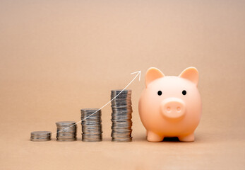 Thin white arrow rising on coin stacks as graph steps near cute pink piggy bank isolated on beige...