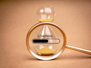 Loading update concept. Word "Loading..." with bar on simple hourglass in magnifying glass lens on beige recycle paper background, minimal style. Setting a time limit, mini-deadline to work.