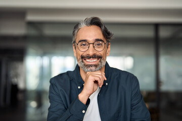 Happy middle aged 50 year old professional business man, smiling older executive ceo manager, smiling entrepreneur wearing glasses sitting at desk in office working looking at camera, portrait.