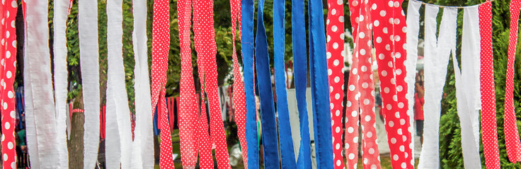 Ribbons of fabric of different colors are strung on a rope and hung on the street. Different colors...