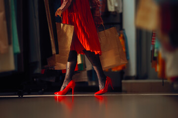 Woman in Red High Heels Shopping in Fashion Store. Elegant fashionista carrying her shopping bags in fashion boutique 
