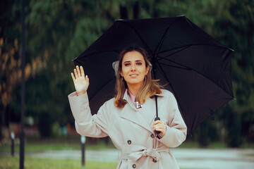 Happy Woman Waving Hello Holding an Umbrella. Cheerful girl saluting on the street during a rainy day
