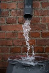 Rännistä valuvaa vettä tynnyriin kaatosateessa. ||| Gutter water flowing into the barrel in pouring rain.