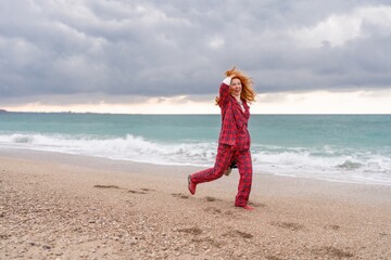 Sea Lady in plaid shirt with a christmas tree in her hands enjoys beach. Coastal area. Christmas, New Year holidays concep