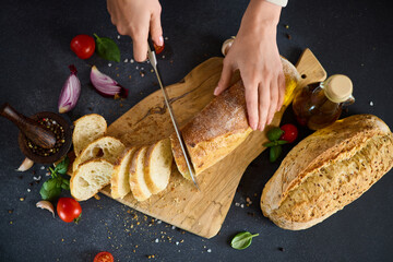 chef cutting Fresh bread on wooden cutting board on kitchen table