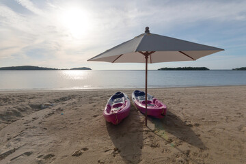 two kayak and beach umbrella on sandy beach with sunny day.