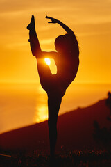 Yoga, sunset and woman with silhouette and body stretching or flexible pose of leg in air in...