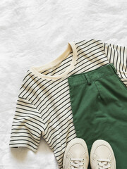 Women's clothing - bermuda cotton shorts, striped t-shirt and textile sneakers on a light background, top view