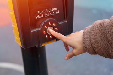 hand pushing up button of traffic light for pedestrians to cross the street safely. Rules for...