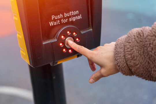 hand pushing up button of traffic light for pedestrians to cross the street safely. Rules for reducing accident