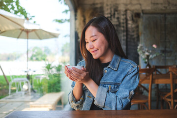Portrait image of a beautiful young asian woman holding and drinking hot coffee in cafe - 797410163