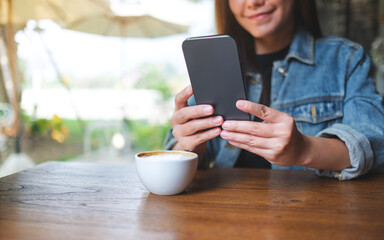 Closeup image of a woman holding and using mobile phone in cafe - 797410320