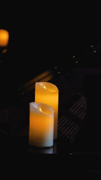 Two electric candles shot in the dark, the reflections from the smaller candle stand out, creating a tranquil atmosphere. Mourning, commemoration and grief for an irrevocable loss