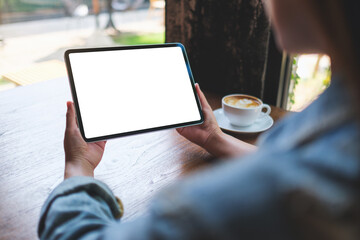 Mockup image of a woman holding digital tablet with blank white desktop screen in cafe - 797410759