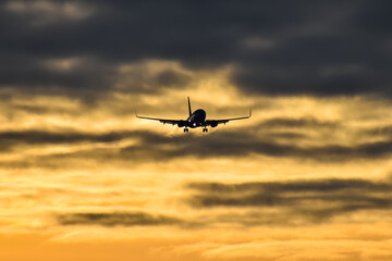 Fototapeta na wymiar commercial airplane coming in for a landing at dusk, with dramatic sky in the background.