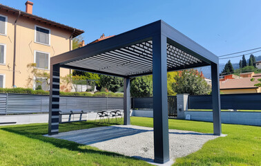 Fototapeta na wymiar an open black and gray modern pergola with metal slats on the roof, standing in front of green grass near house walls. The background is clear blue sky without clouds