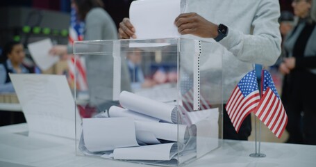 Close up shot of polling box standing on table in polling station. American voters come and put...
