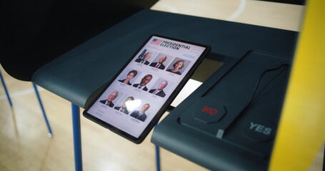 List of American presidential candidates displayed on the tablet screen. Voting booth with tablet computer and buttons. Modern digital voting technology. Election Day in the United States of America.