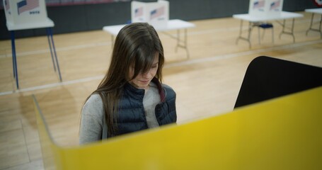 Caucasian woman makes choice and votes in voting booth at polling station, then leaves. Female...
