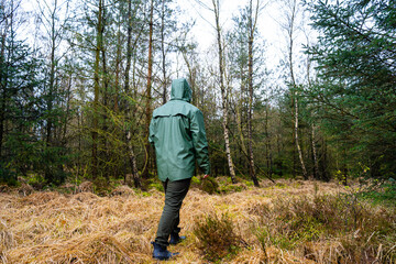 Man in green raincoat walking in the forest