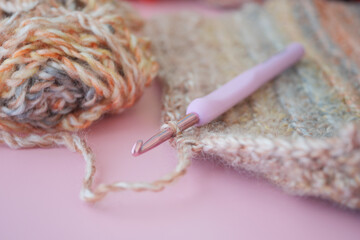 Close up of a crochet hook on magenta yarn on pink surface