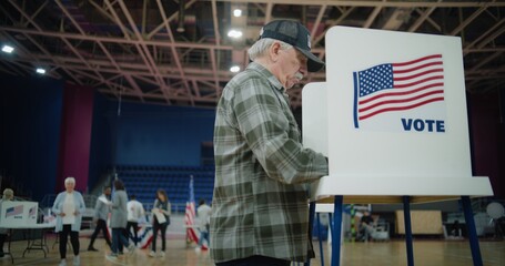 Elderly voter with bulletin in hands comes to voting booth. Diverse American citizens come to vote...