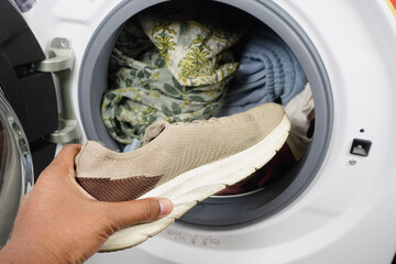  putting dirty shoe in a washing machine.