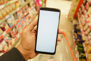 hand holding mobile phone with white screen while shopping at supermarket. 