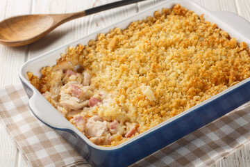 Chicken Cordon Bleu casserole layered together, it's a warm and comforting weeknight meal close up in the baking dish on the white wooden table. Horizontal