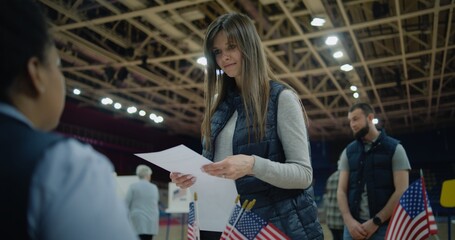 Polling officer consults voters and gives them bulletins. American citizens come to vote in polling...
