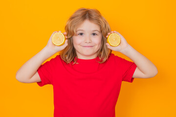 Kids face with fruits. Child hold lemon in studio. Studio portrait of cute kid boy with lemon isolated on yellow.