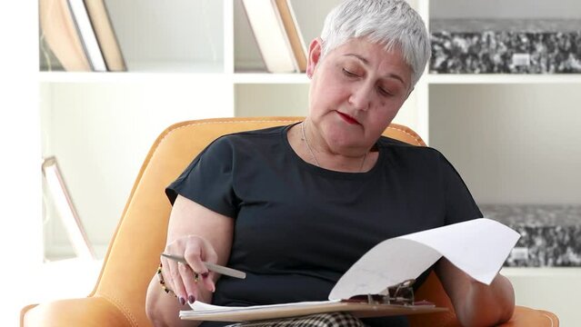 senior woman at home reading and reviewing document or paper