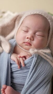 A vertical video of a Taiwanese one-month-old baby wrapped in a blue wrap and taken a newborn photo
台湾人の生後一ヶ月の赤ちゃんが青いおくるみを巻かれてニューボーンフォトを撮影されている縦長動画