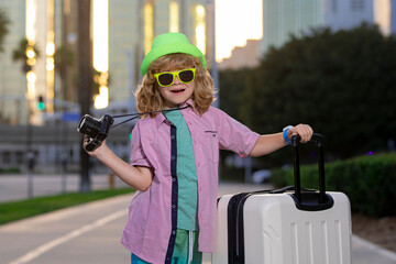 Portrait of happy child traveler with luggage. Positive little tourist with suitcase ready to travelling. Happy kid tourist with baggage going to travel on holidays.