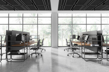 Stylish office coworking interior with pc monitors and chairs in row, window