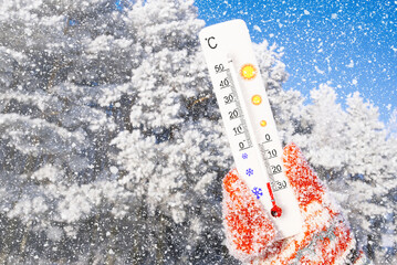 Winter holidays with snow. White celsius scale thermometer in hand. Ambient temperature minus 24 degrees celsius