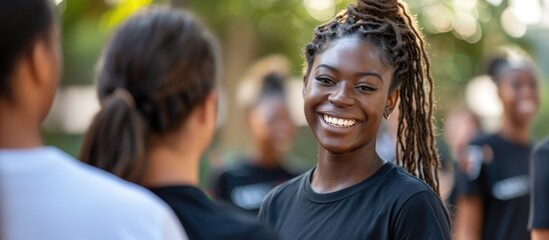 A woman with dreadlocks is smiling while standing in front of a group of people at a college event